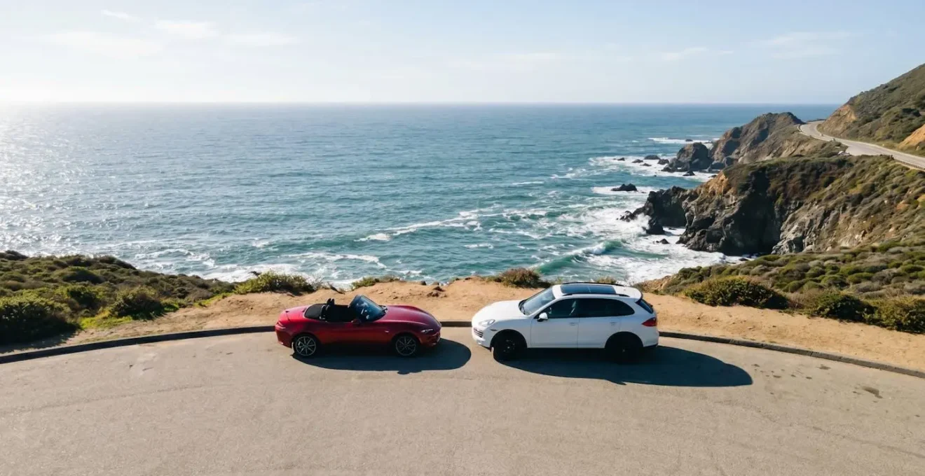 Vue aérienne d'une Mustang rouge et d'un SUV blanc côte à côte sur la mythique Highway 1 californienne