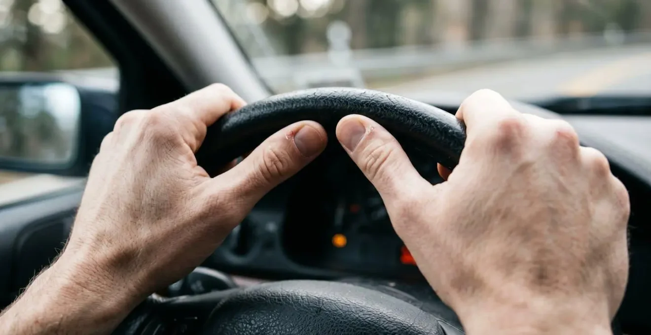 Vue rapprochée des mains du conducteur appliquant une pression ferme sur le volant