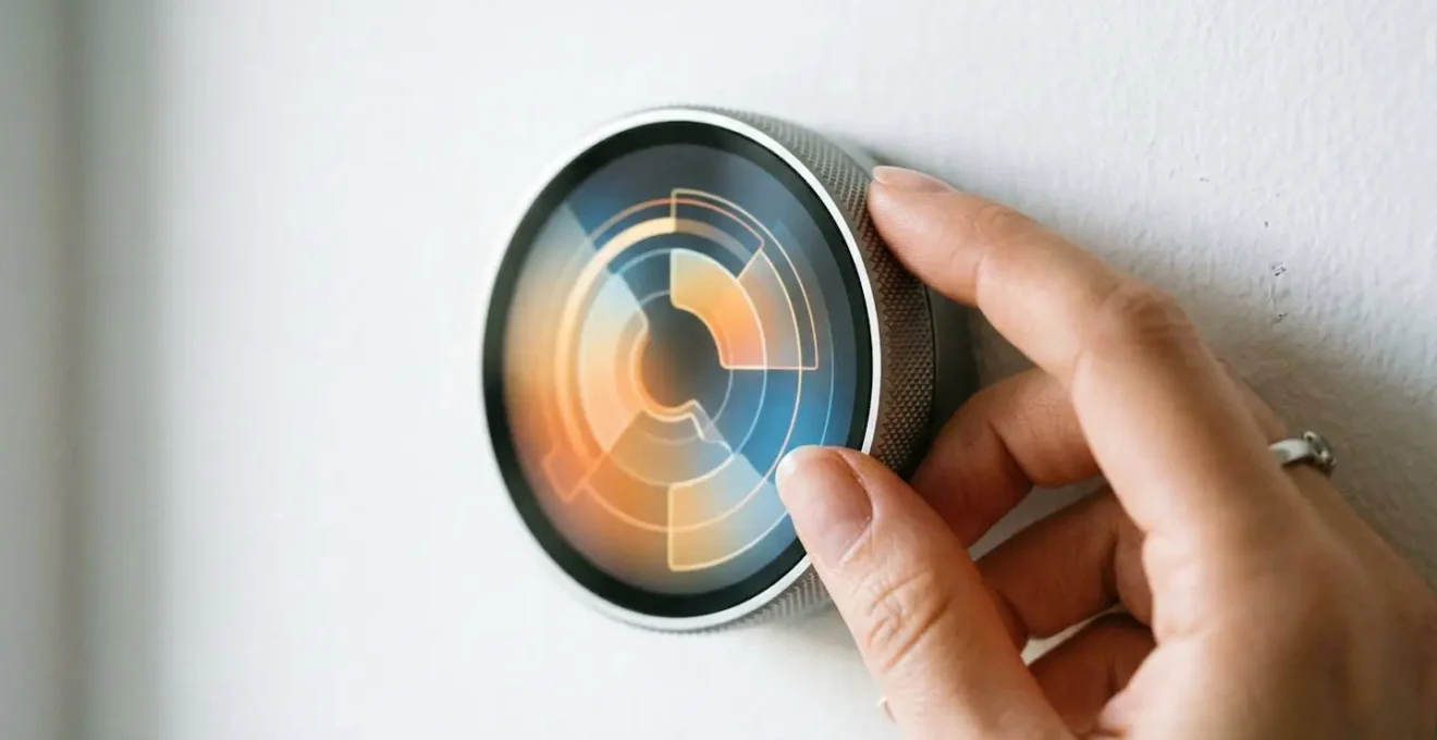 Main ajustant un thermostat programmable avec courbe de température hebdomadaire en arrière-plan flou