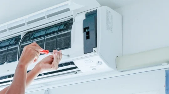 Un technicien CVCA installe une thermopompe murale dans le salon d'un duplex québécois en hiver.